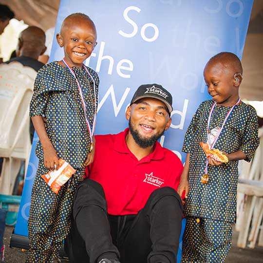 two children with hearing aids and with a Starkey Staff